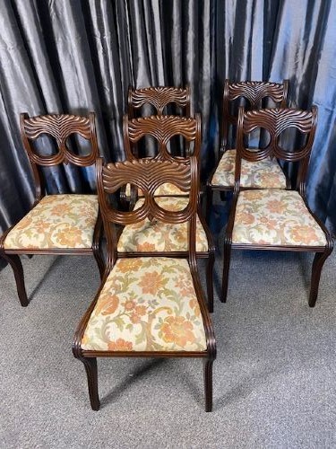 A set of six carved mahogany dining chairs featuring openwork backrests and floral patterned upholstered seats.