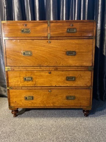 A nineteenth-century mahogany military campaign chest of drawers featuring flush brass handles, protective corner mounts, and turned feet.