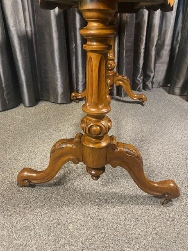 A Victorian burr walnut occasional table featuring a serpentine top with symmetrical book-matched grain, carved end-supports, and a central turned stretcher. View IV