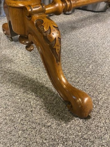 A Victorian burr walnut occasional table featuring a serpentine top with symmetrical book-matched grain, carved end-supports, and a central turned stretcher. View V