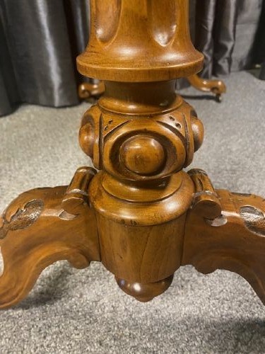 A Victorian burr walnut occasional table featuring a serpentine top with symmetrical book-matched grain, carved end-supports, and a central turned stretcher. View VI