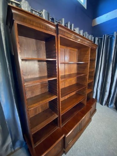 A large mahogany breakfront bookcase featuring a projecting central section with adjustable open shelves above a solid wooden plinth base. View II
