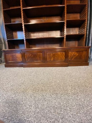 A large mahogany breakfront bookcase featuring a projecting central section with adjustable open shelves above a solid wooden plinth base. View III