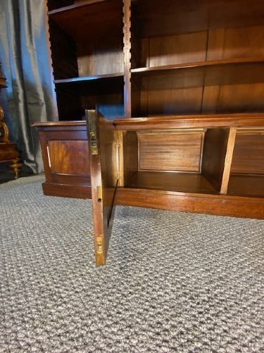A large mahogany breakfront bookcase featuring a projecting central section with adjustable open shelves above a solid wooden plinth base. View IV