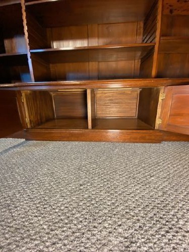 A large mahogany breakfront bookcase featuring a projecting central section with adjustable open shelves above a solid wooden plinth base. View V