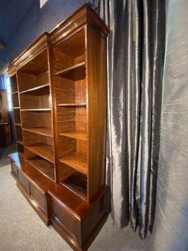 A large mahogany breakfront bookcase featuring a projecting central section with adjustable open shelves above a solid wooden plinth base. View VI