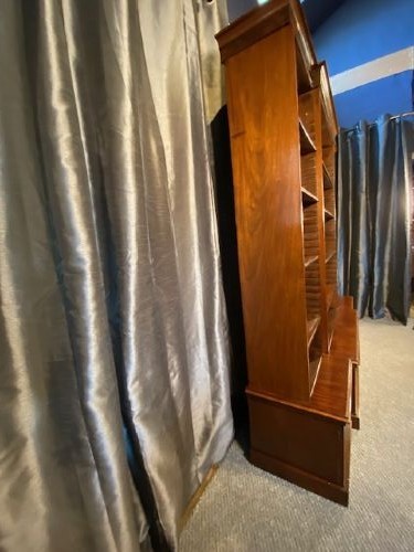 A large mahogany breakfront bookcase featuring a projecting central section with adjustable open shelves above a solid wooden plinth base. View VII