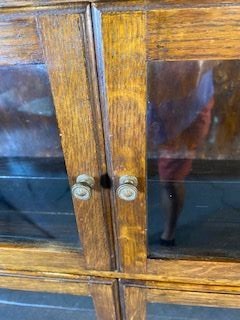An Edwardian medium brown oak four-tier bookcase featuring glazed double doors on each shelf and a moulded top cornice. View II