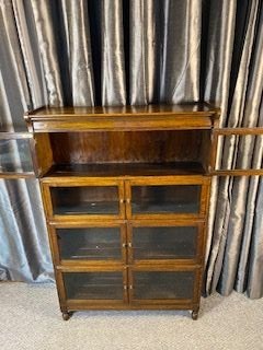 An Edwardian medium brown oak four-tier bookcase featuring glazed double doors on each shelf and a moulded top cornice. View VI