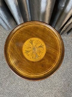 An antique warm brown mahogany wine table featuring a circular top with satinwood central inlay and a fluted turned pedestal resting on three cabriole legs. View II