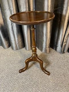 A small mahogany wine table featuring a circular top with a raised rim, supported by a central turned pedestal and a tripod base with cabriole legs.