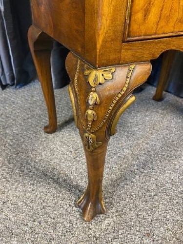 A matching pair of burr walnut bedside cabinets featuring shaped galleried shelf tops, shell carvings, double cupboard doors, and cabriole legs. View VI