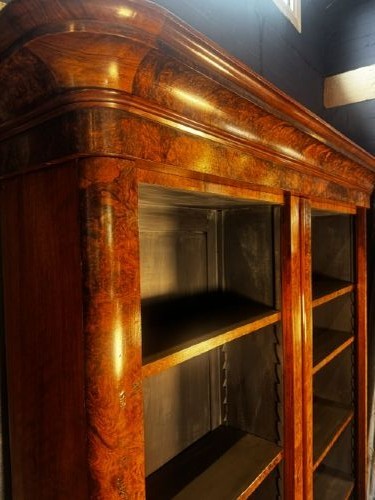 A large double-bay open bookcase made of burr walnut veneer with a moulded top cornice and dark interior shelving. View II