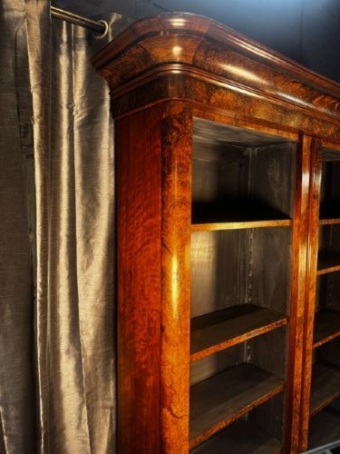 A large double-bay open bookcase made of burr walnut veneer with a moulded top cornice and dark interior shelving. View III