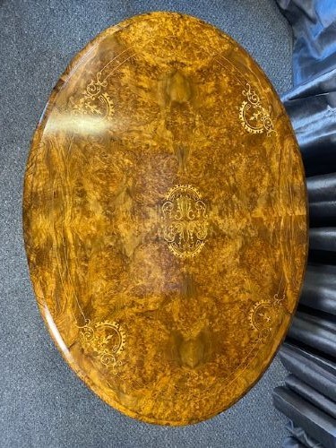 An oval burr walnut coffee table featuring floral marquetry inlay, a moulded rim, and carved splayed legs. View II