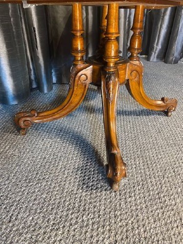 An oval burr walnut coffee table featuring floral marquetry inlay, a moulded rim, and carved splayed legs. View VI