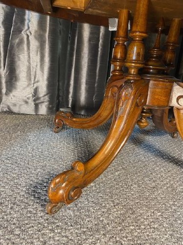 An oval burr walnut coffee table featuring floral marquetry inlay, a moulded rim, and carved splayed legs. View VII