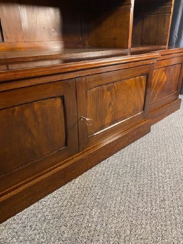 A large Victorian mahogany open breakfront bookcase featuring three sectioned shelving units over a low plinth cabinet base. View V