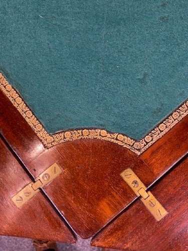 An Edwardian mahogany envelope card table featuring marquetry floral inlay on four triangular folding top leaves, a single drawer with brass handles, and square tapered legs. View VI