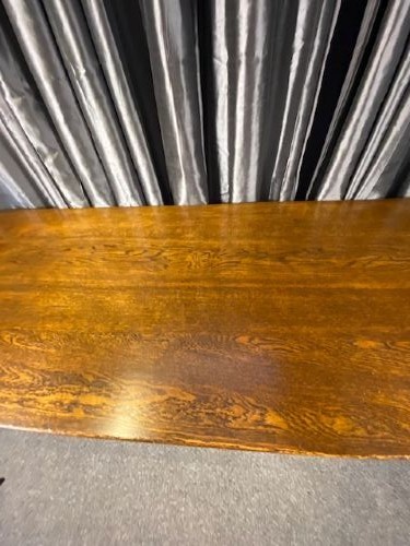 A solid oak refectory dining table featuring a rectangular plank top supported by a sturdy trestle base with a central stretcher rail. View V