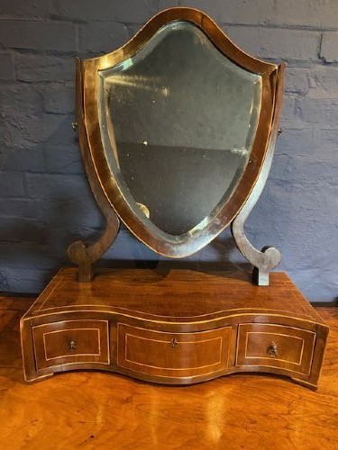 An antique mahogany shield-shaped swing mirror mounted on a serpentine base with three inlaid drawers and brass knobs. View II