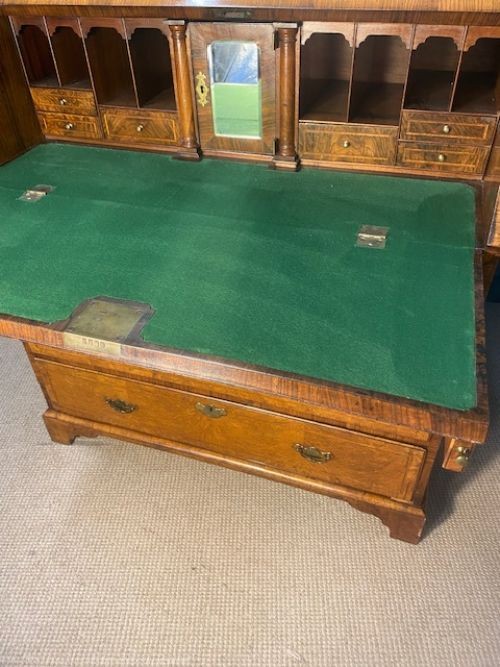 An antique walnut bureau bookcase featuring a broken arch pediment, double mirrored cabinet doors, a slant-front writing slope, and several drawers with brass handles. View II