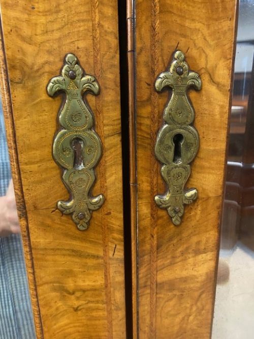An antique walnut bureau bookcase featuring a broken arch pediment, double mirrored cabinet doors, a slant-front writing slope, and several drawers with brass handles. View V