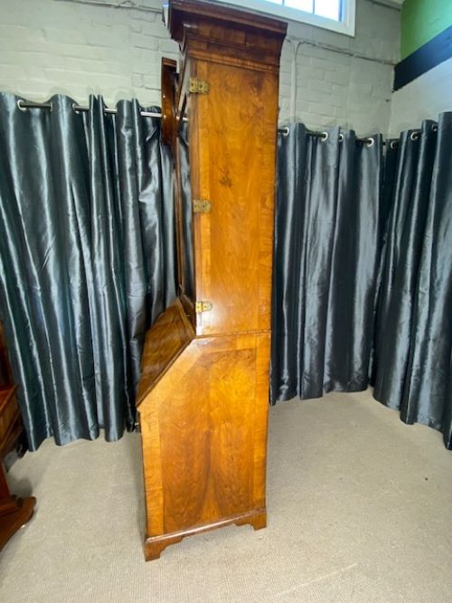 An antique walnut bureau bookcase featuring a broken arch pediment, double mirrored cabinet doors, a slant-front writing slope, and several drawers with brass handles. View VIII