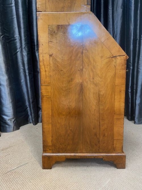 An antique walnut bureau bookcase featuring a broken arch pediment, double mirrored cabinet doors, a slant-front writing slope, and several drawers with brass handles. View IX