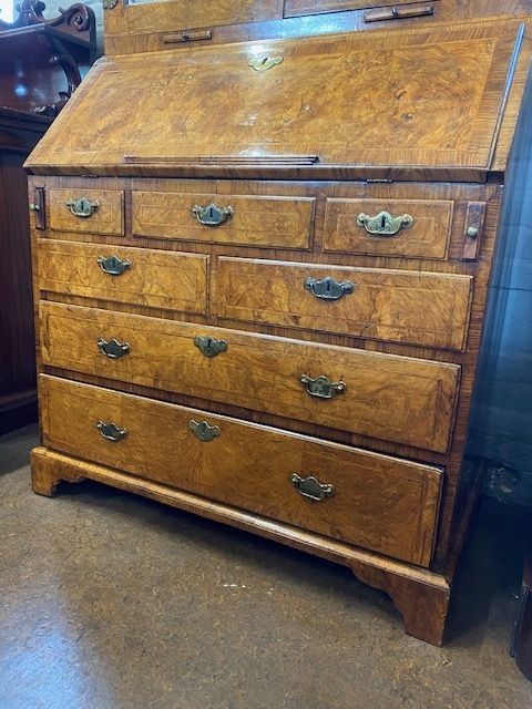 An antique walnut bureau bookcase featuring a broken arch pediment, double mirrored cabinet doors, a slant-front writing slope, and several drawers with brass handles. View X