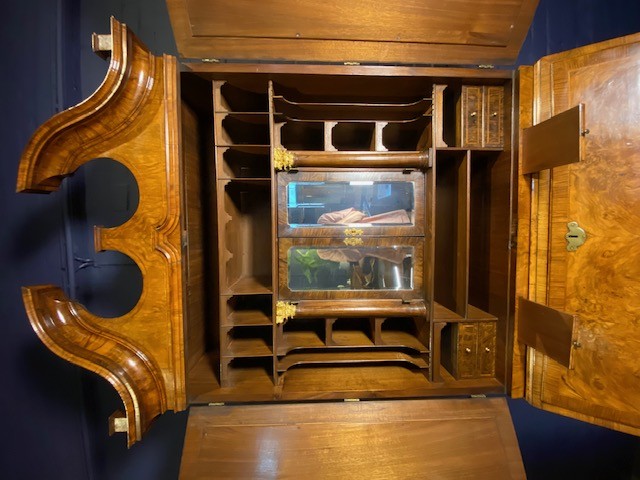 An antique walnut bureau bookcase featuring a broken arch pediment, double mirrored cabinet doors, a slant-front writing slope, and several drawers with brass handles. View XIII