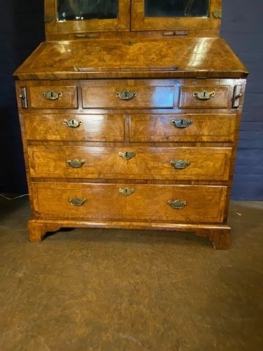 An antique walnut bureau bookcase featuring a broken arch pediment, double mirrored cabinet doors, a slant-front writing slope, and several drawers with brass handles. View XIV