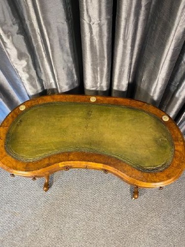 An antique kidney-shaped walnut writing desk featuring an inset green leather writing surface, frieze drawers, turned legs, and a stretcher base. View II