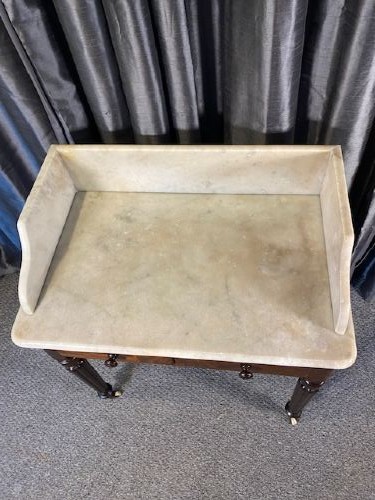 A Victorian mahogany washstand featuring a white marble top with splashback, twin drawers, and turned reeded legs on brass castors. View IV