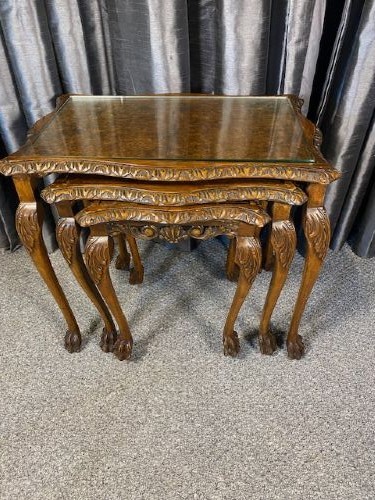 A set of three graduated walnut nesting tables featuring glass tops, shell carvings on the frieze, and cabriole legs.