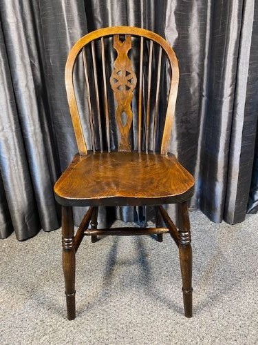A set of four antique English country Windsor dining chairs featuring hoop backs, wheelback central splats, shaped elm seats, and turned legs. View II