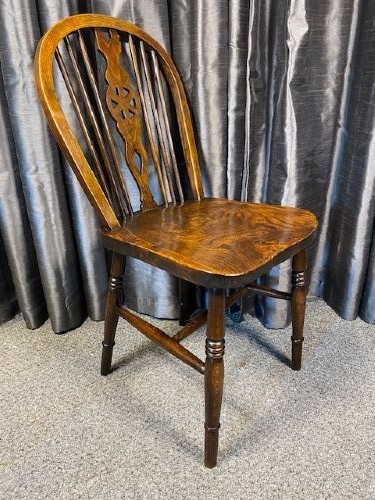 A set of four antique English country Windsor dining chairs featuring hoop backs, wheelback central splats, shaped elm seats, and turned legs. View III