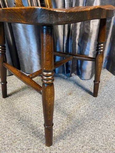 A set of four antique English country Windsor dining chairs featuring hoop backs, wheelback central splats, shaped elm seats, and turned legs. View V