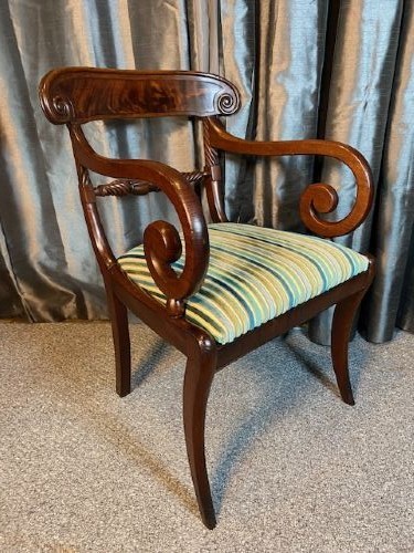 A pair of antique Regency mahogany carver chairs featuring curved scroll arms, carved crossbars, striped fabric upholstered seats, and sabre legs. View II
