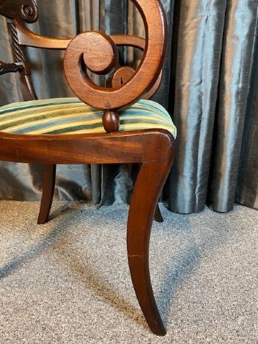 A pair of antique Regency mahogany carver chairs featuring curved scroll arms, carved crossbars, striped fabric upholstered seats, and sabre legs. View IV