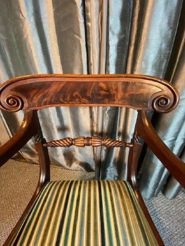 A pair of antique Regency mahogany carver chairs featuring curved scroll arms, carved crossbars, striped fabric upholstered seats, and sabre legs. View V