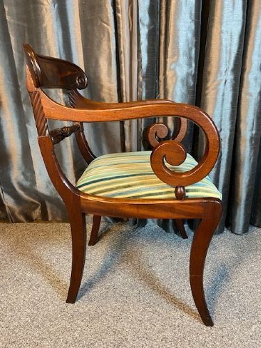 A pair of antique Regency mahogany carver chairs featuring curved scroll arms, carved crossbars, striped fabric upholstered seats, and sabre legs. View VI
