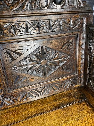 A dark carved oak storage bench featuring a high backrest with geometric floral panels and a enclosed box seat base. View IV
