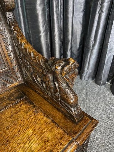 A dark carved oak storage bench featuring a high backrest with geometric floral panels and a enclosed box seat base. View V