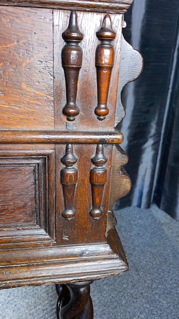 A dark oak side table featuring two drawers with geometric mouldings, brass teardrop handles, barley twist legs, and matching lower stretchers. View V