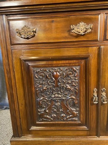 A tall Victorian walnut bookcase featuring a two-door glazed upper display section, two middle drawers with metal handles, and carved panel doors at the base. View III