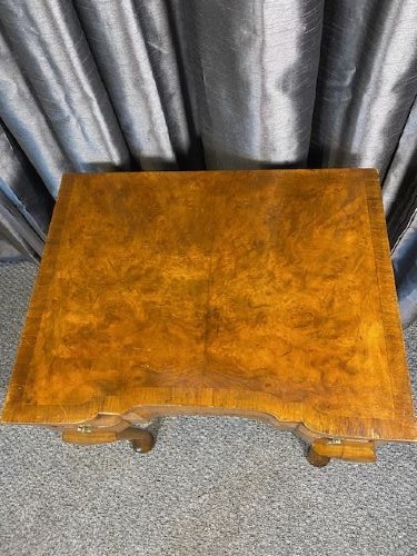 A Queen Anne style burr walnut occasional table featuring cabriole legs, pad feet, a shaped apron, and brass drop handles. View II