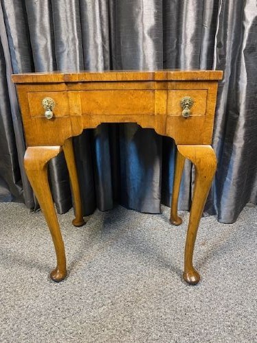 A Queen Anne style burr walnut occasional table featuring cabriole legs, pad feet, a shaped apron, and brass drop handles. View III