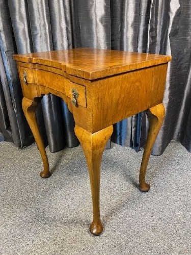 A Queen Anne style burr walnut occasional table featuring cabriole legs, pad feet, a shaped apron, and brass drop handles. View IV