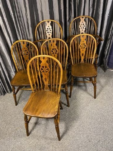 A set of six brown wooden Windsor dining chairs with hoop backs, pierced wheelback central splats, and turned legs.